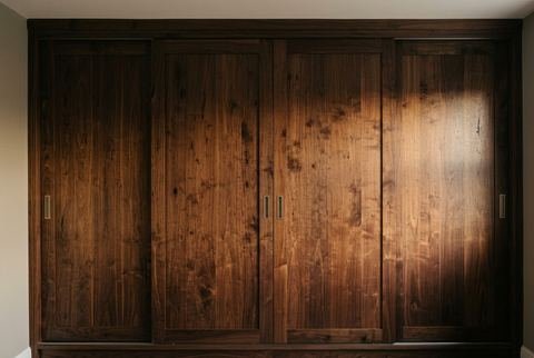 Armario empotrado de cuatro puertas correderas en madera de nogal con tiradores empotrados
