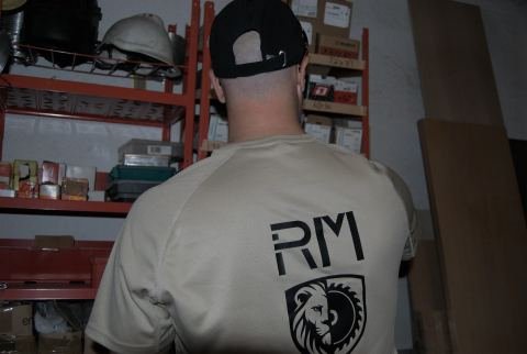 Carpintero de IRM Carpinteros en el taller de Vinaròs, de espaldas, con la camiseta del escudo del león y la sierra